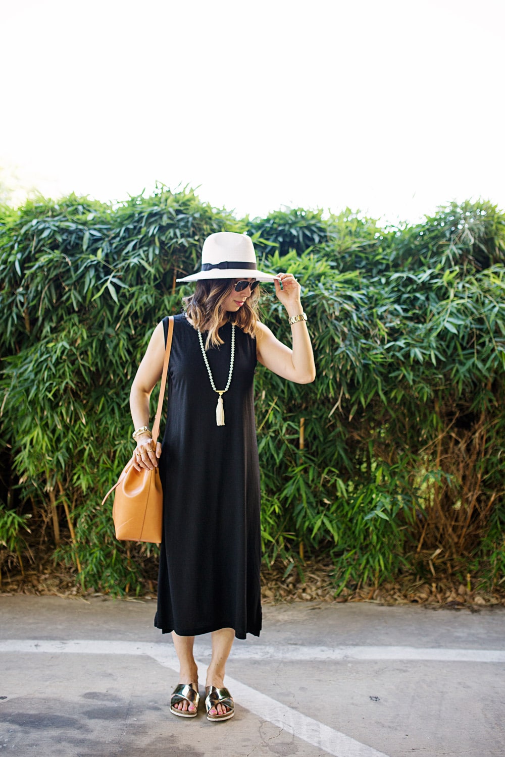 black sleeveless midi dress with panama hat and gold slides