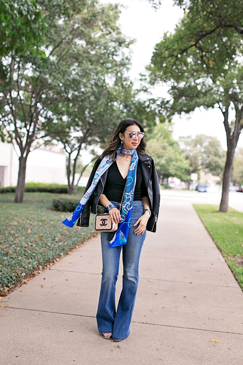 blue hermes maxi twilly with black top, flare jeans, and moto jacket