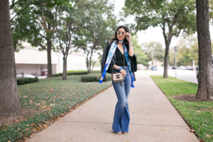 blue hermes maxi twilly with black top, flare jeans, and moto jacket