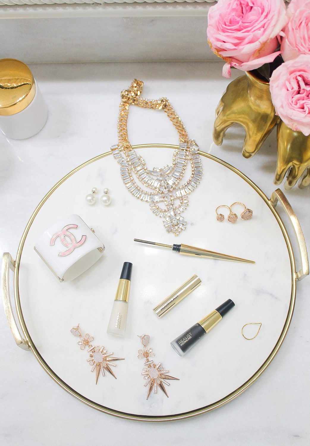 flatlay with hourglass lash curator, chanel cuff, statement necklace, kendra scott isadora earrings
