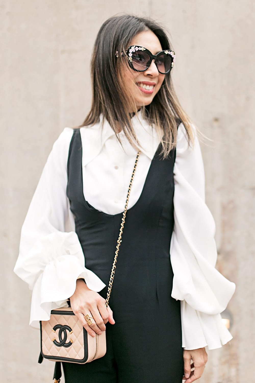 black jumpsuit with statement sleeve blouse and chanel vanity bag black and cream