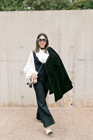 black jumpsuit with statement sleeve blouse and chanel vanity bag black and cream