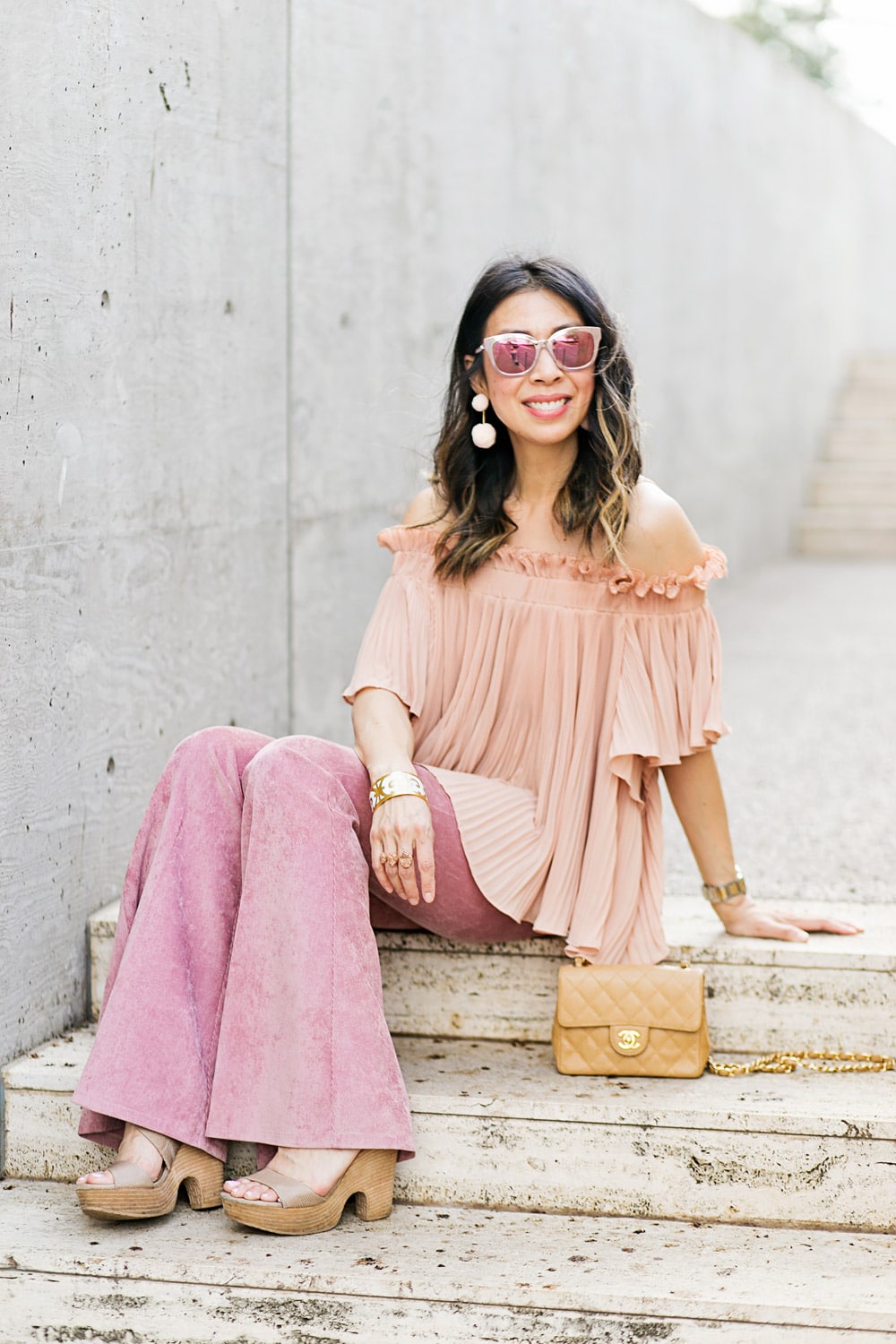 baublebar bahama pink pom pm earrings with endless rose pink pleated off the shoulder top and pink flare corduroy pants, chanel caviar mini flap, dior diorama pink mirrored sunglasses, spring outfit idea