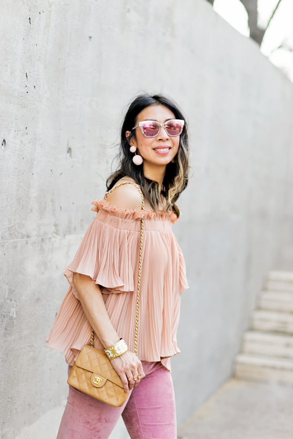baublebar bahama pink pom pm earrings with endless rose pink pleated off the shoulder top and pink flare corduroy pants, chanel caviar mini flap, dior diorama pink mirrored sunglasses, spring outfit idea 