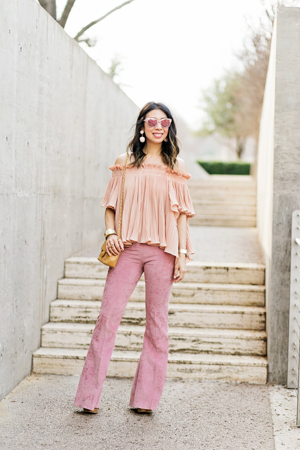 baublebar bahama pink pom pm earrings with endless rose pink pleated off the shoulder top and pink flare corduroy pants, chanel caviar mini flap, dior diorama pink mirrored sunglasses, spring outfit idea 