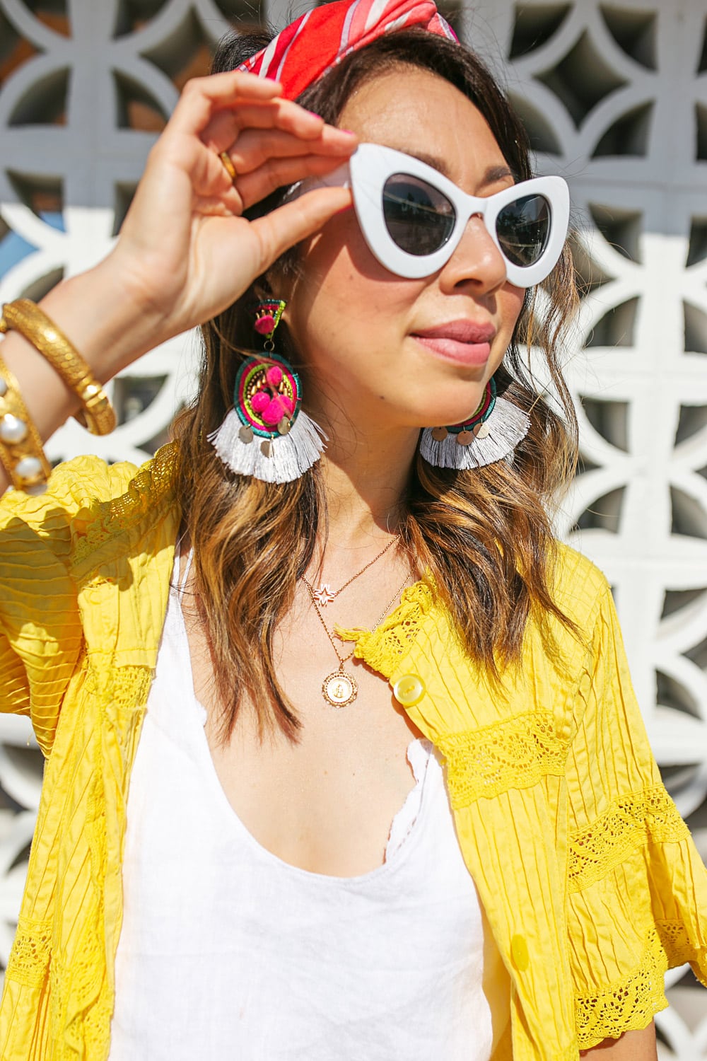style of sam in yellow cardigan pink headscarf fringe statement earrings white cat-eye sunglasses