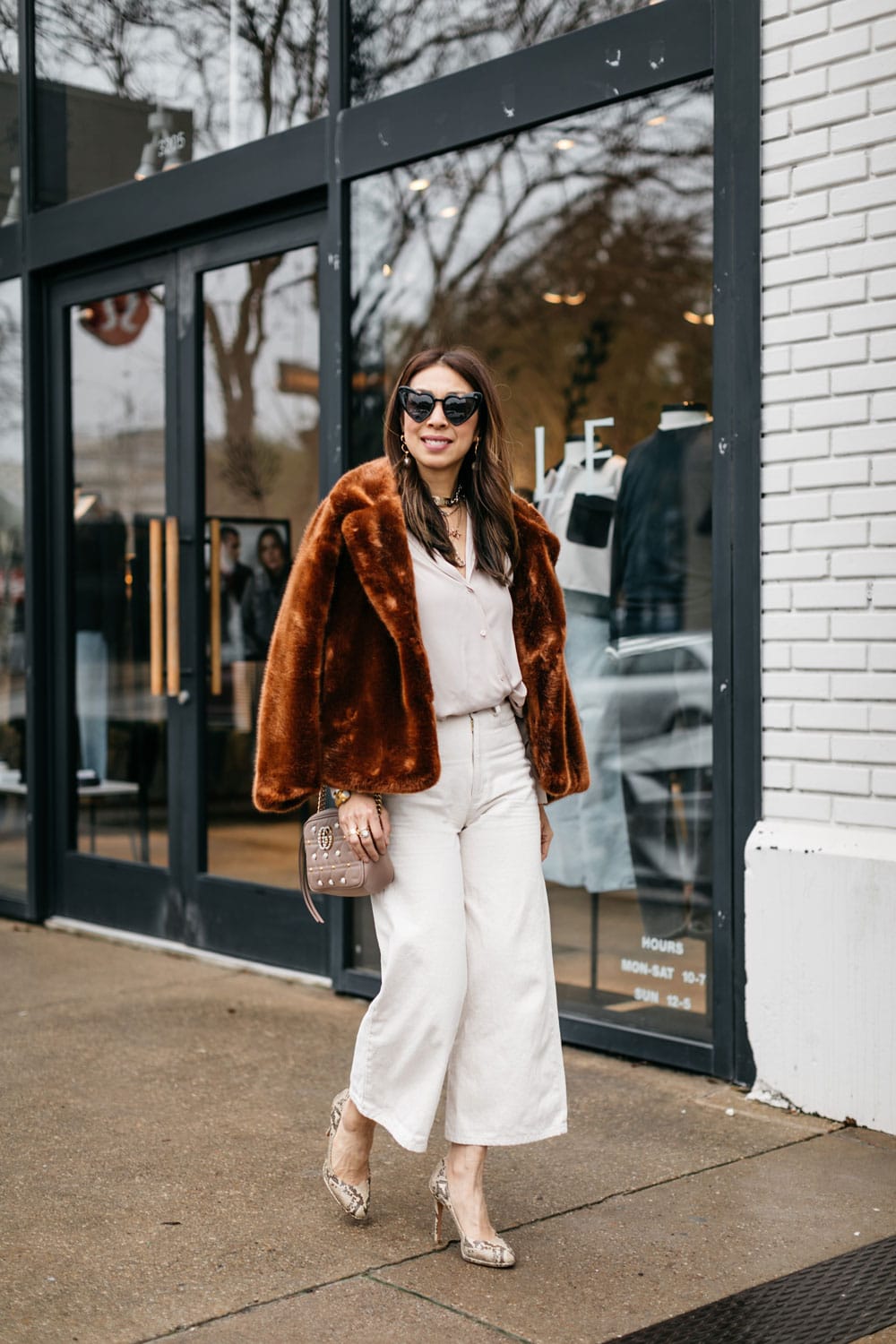 style of sam in faux wrap top winter white outfit, brown faux fur jacket, heart shaped sunglasses, no pink or red valentine's day outfit